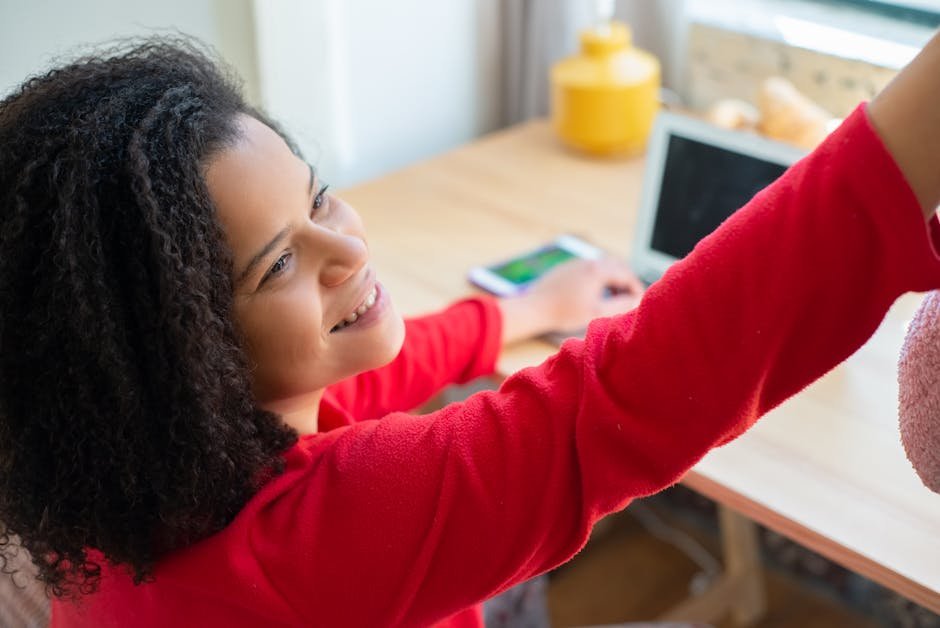 Smiling woman with curly hair enjoying a moment indoors, reaching out with joy.